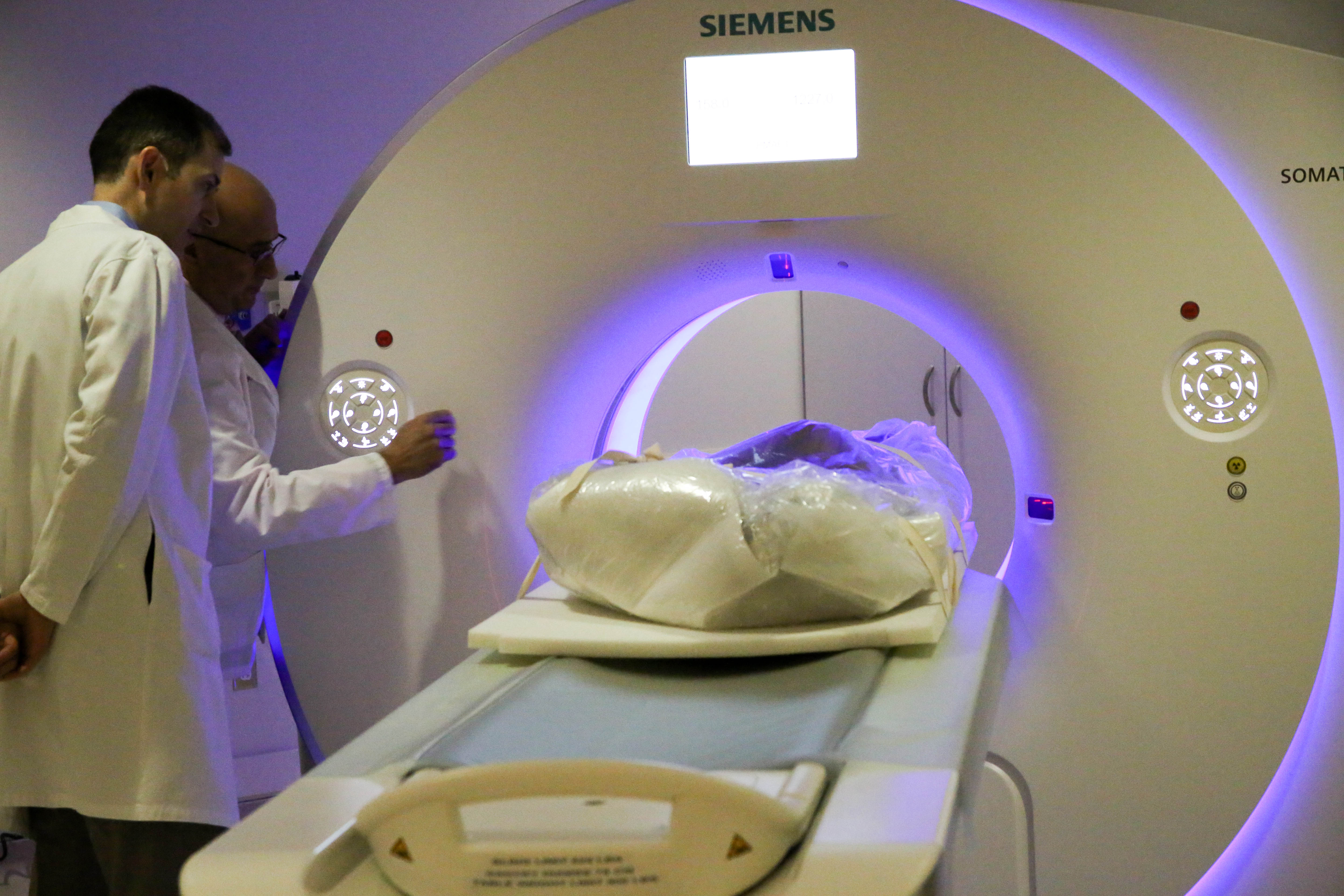 Researchers watch as the mummy travels into the CT machine.