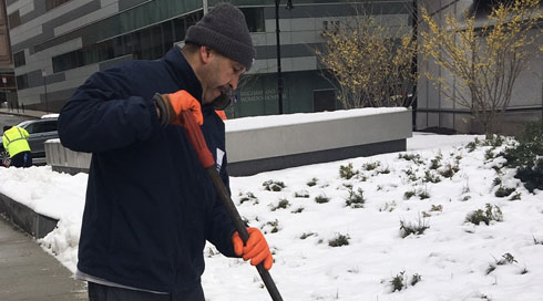 Ruberkis Arias, of Environmental Services, shovels snow outside the Hale Building for Transformative Medicine.