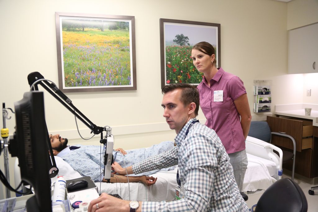 Christopher Doughty (center) demonstrates an electromyography test for Nichole Bluemle (right). 