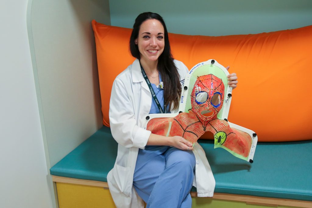 Marianne Weiler displays a radiation therapy mask for pediatric patients painted to resemble Spider-Man.